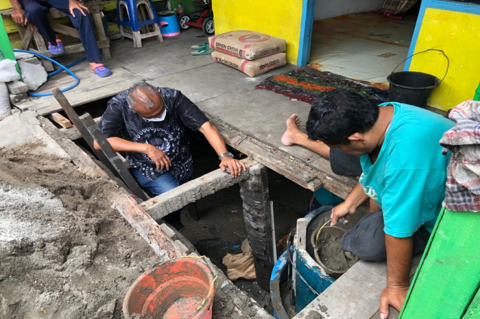 DR. Koen membantu timnya saat membuat septic tank dalam air di depan rumah panggung yang berada diatas permukaan air sungai 
